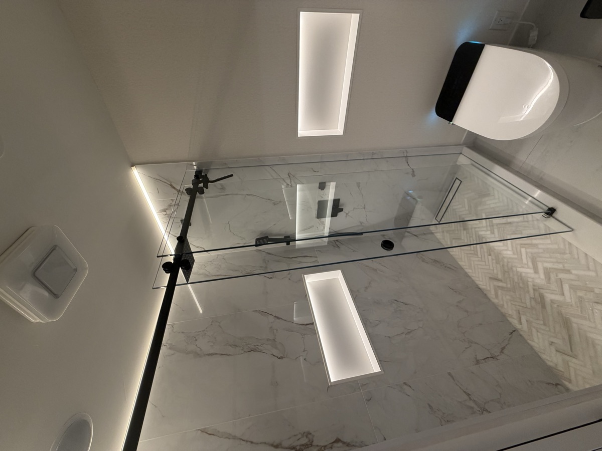 Marble-look shower with lit niches and black fixtures